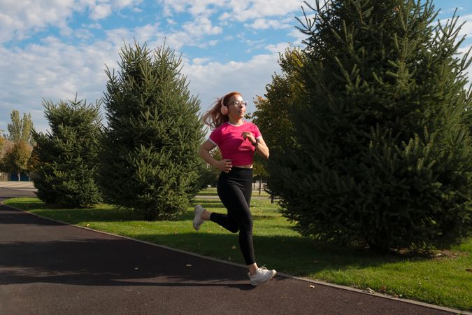 Female runner in park, jogging with headphones