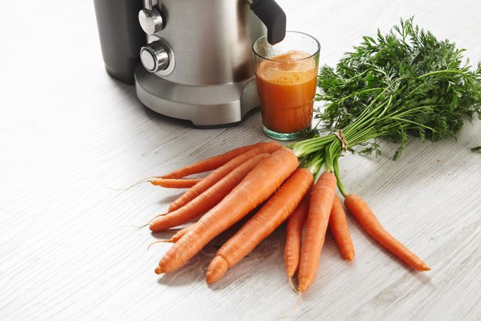 Bunch of carrots in front of professional juicing equipment