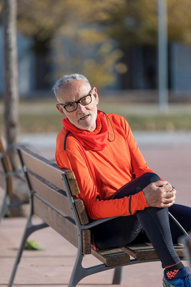 Older male sitting in park bench looking at camera