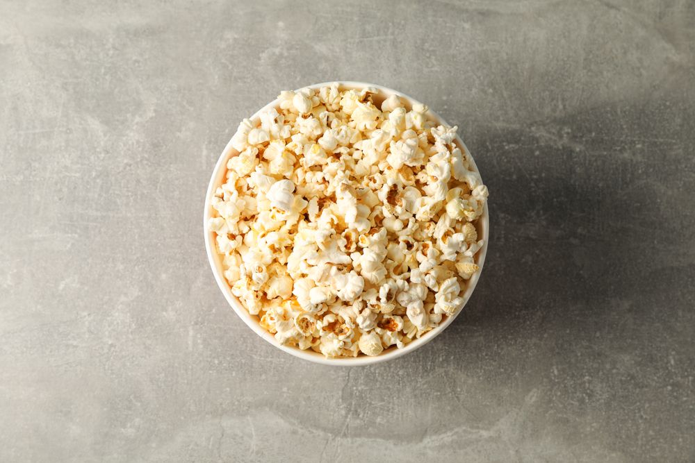 Bucket with popcorn on grey background, space for text