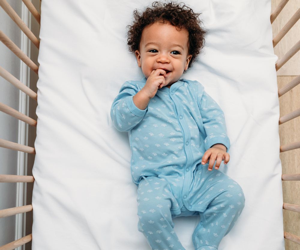 Smiling baby boy lying down in his crib