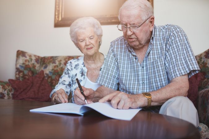 Indoor shot of older couple at home signing paperwork together