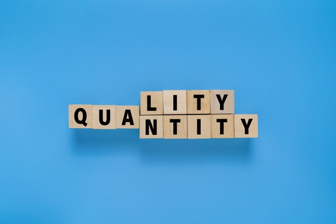 wooden blocks with quality and quantity words. isolated on blue background