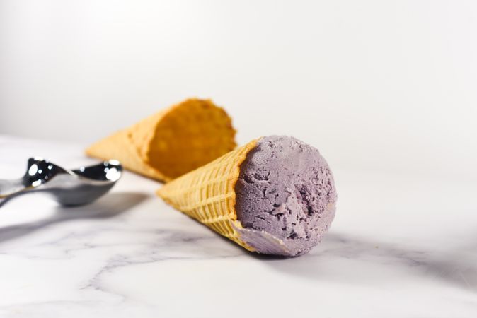 Purple ice cream cone lying on it's side on marble table