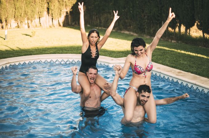 Guys with woman on their shoulders in pool
