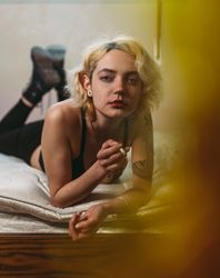 Confident pensive freckled woman smoking on bed