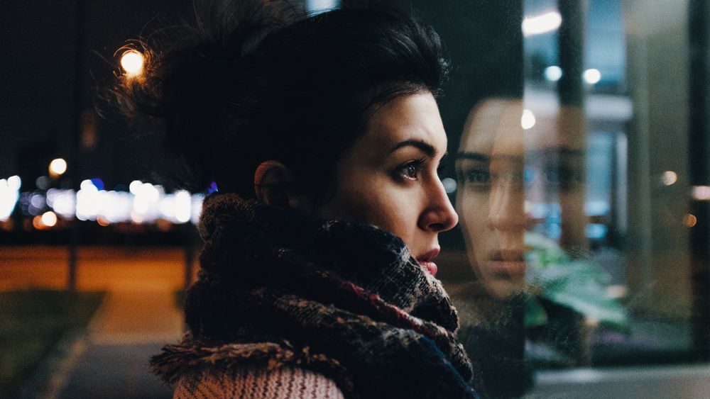 Woman looking through window during nighttime