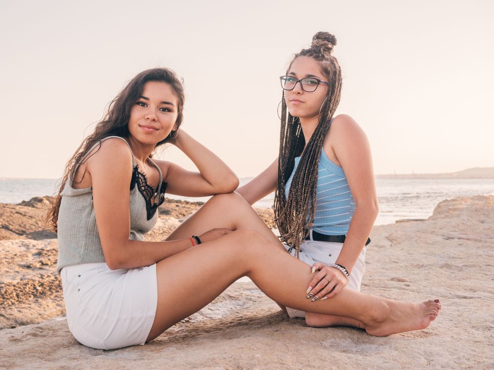 Smiling trendy young women relaxing on seashore
