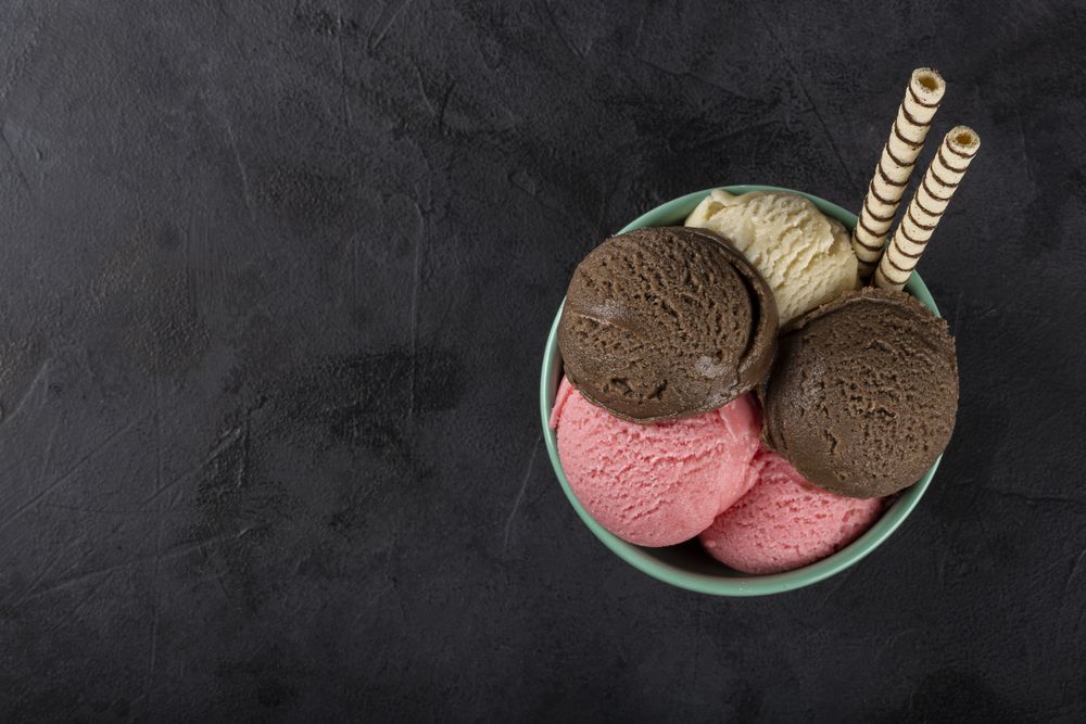 Bowl with Neapolitan ice cream on dark background.