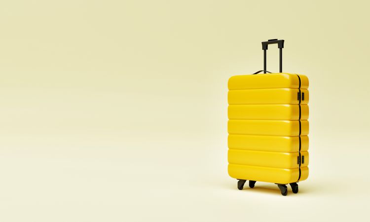 Single yellow hard shell roller suitcase on light yellow background