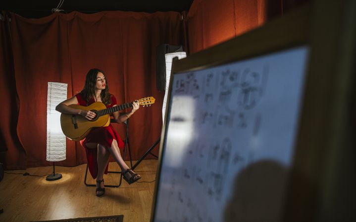 Creative woman singing and playing guitar on stage
