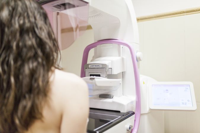 Female patient beside digital mammography unit