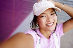 Happy female looking up and smiling at camera while taking selfie
