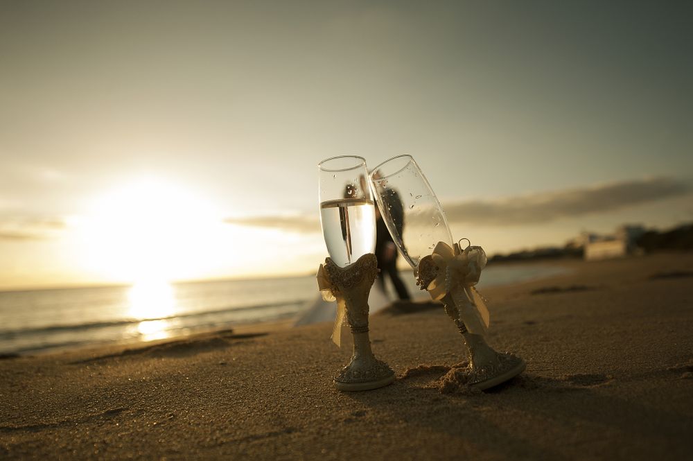 Woman and man embracing on seashore with glasses of champagne