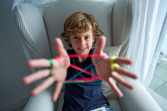 Cheerful boy playing cats cradle game
