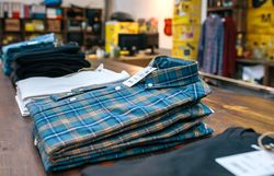 Organized blue plaid shirt stack over counter on vintage clothes shop