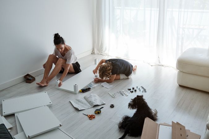 Mother and son assembling table in room with dog