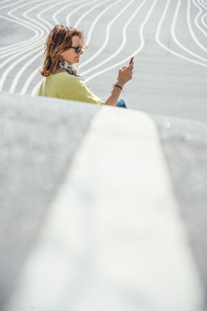 Modern relaxed woman on marked road and browsing smartphone