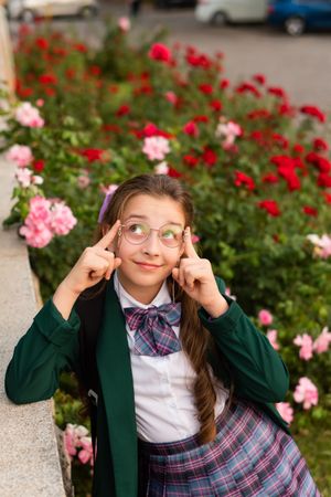 Young girl posing surrounded by pink and red flowers.