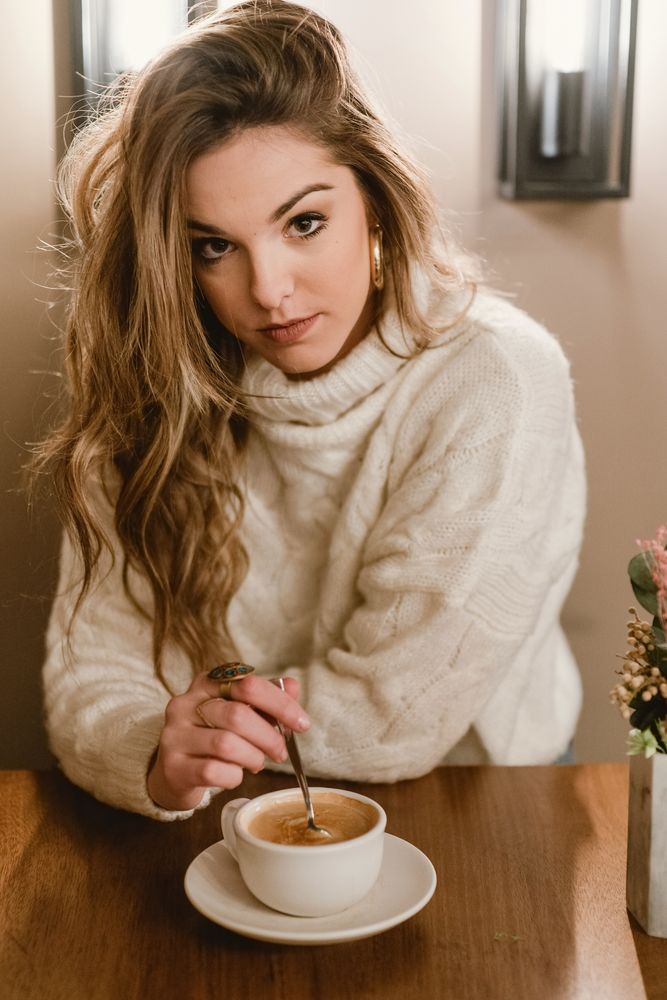Elegant woman mixing coffee in cafe