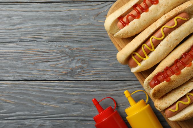 Tasty hot dogs and sauces on gray wooden background