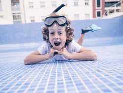 Amazed cute boy lying on bottom of empty pool