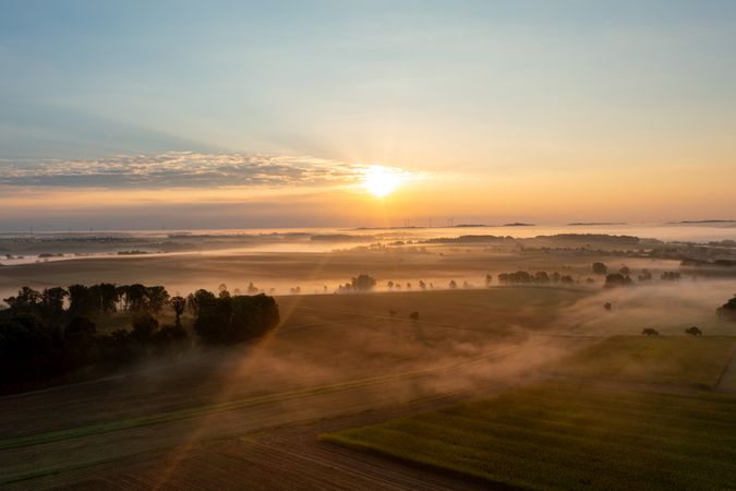 Sunrise aerial view at golden hour with foggy rolling agricultural fields