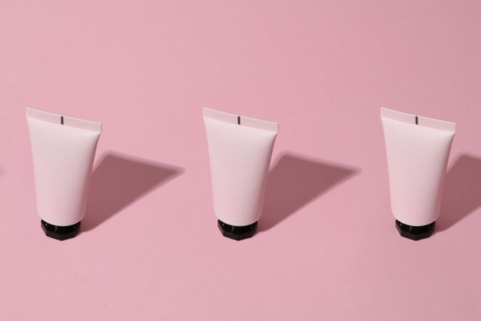 Tube of cosmetic on pink background, space for text