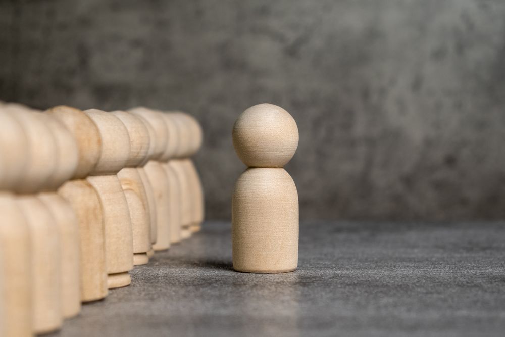 one wooden figure stand out from the crowd. leadership, uniqueness and differentiation concept