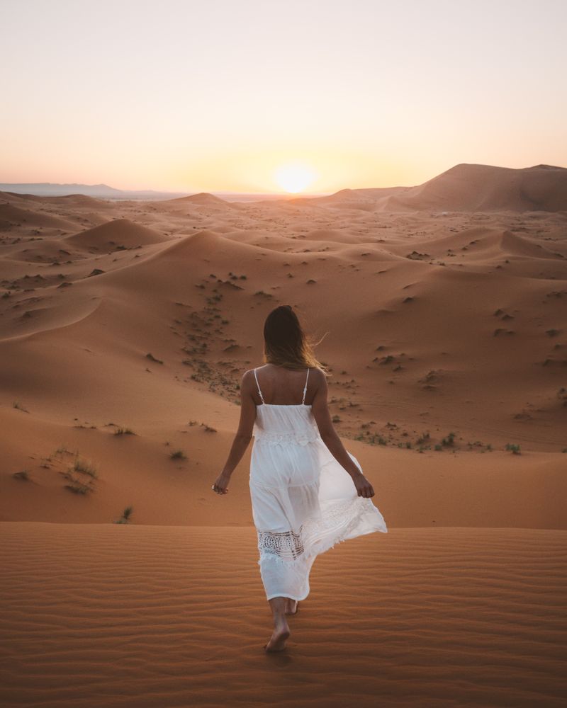 Woman in white dress walking in desert