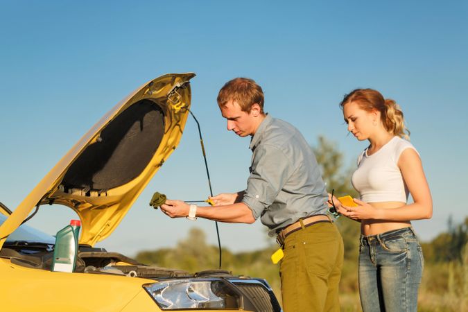 Boyfriend and girlfriend checking engine on side of road