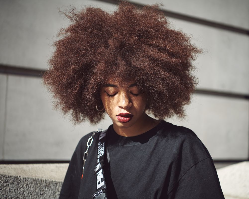 London, England, United Kingdom - September 15th, 2019: Portrait of woman with afro looking down