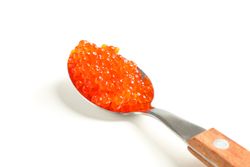 Spoon with red caviar isolated on blank background, closeup