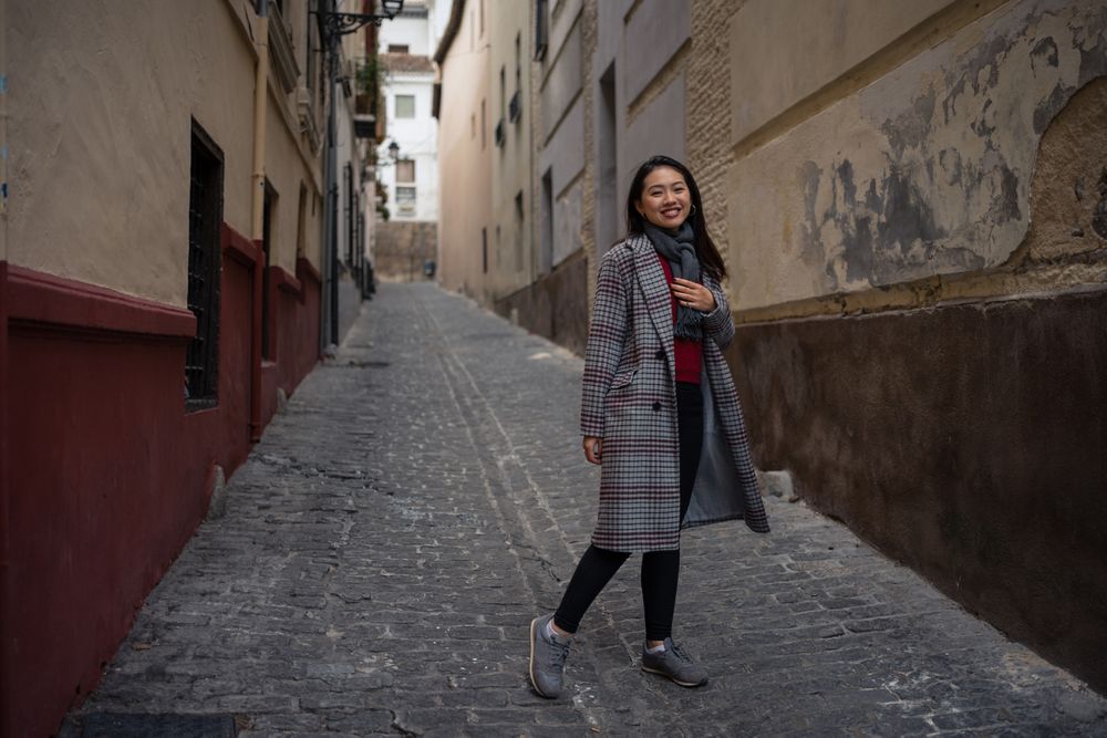 Joyful Asian resting female hiking on old rocked narrow street