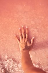 Female holding healing salt pile in pink water