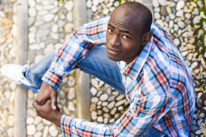 Male in plaid shirt sitting on stairs and looking up