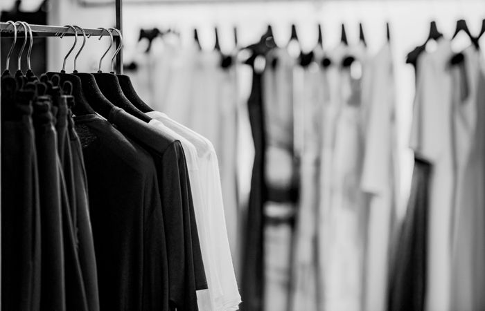 Grayscale photo of clothes racks in fashion store