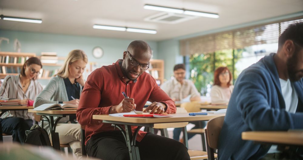 Black Man Writing Down Notes in Notebook.