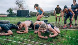 Participants in an obstacle course crawling