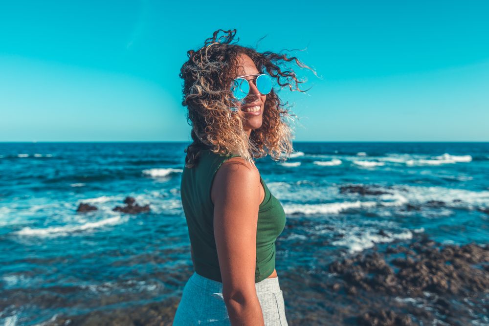 Stylish woman standing near sea