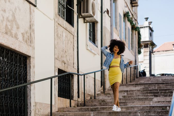 Stylish female standing on stairs with railing outdoors