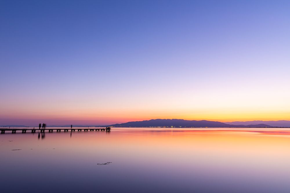 Anonymous tourists on pier during sundown
