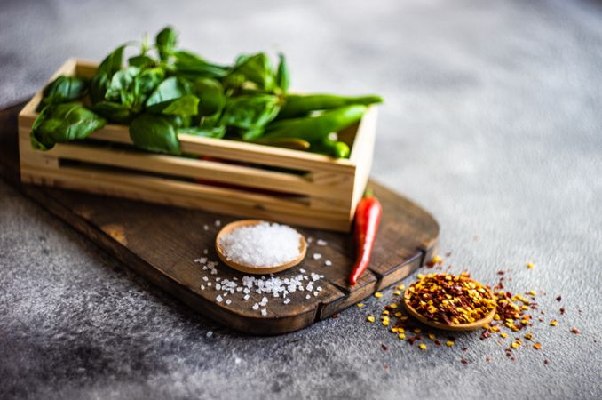 Peppers and basil in basket on cutting board