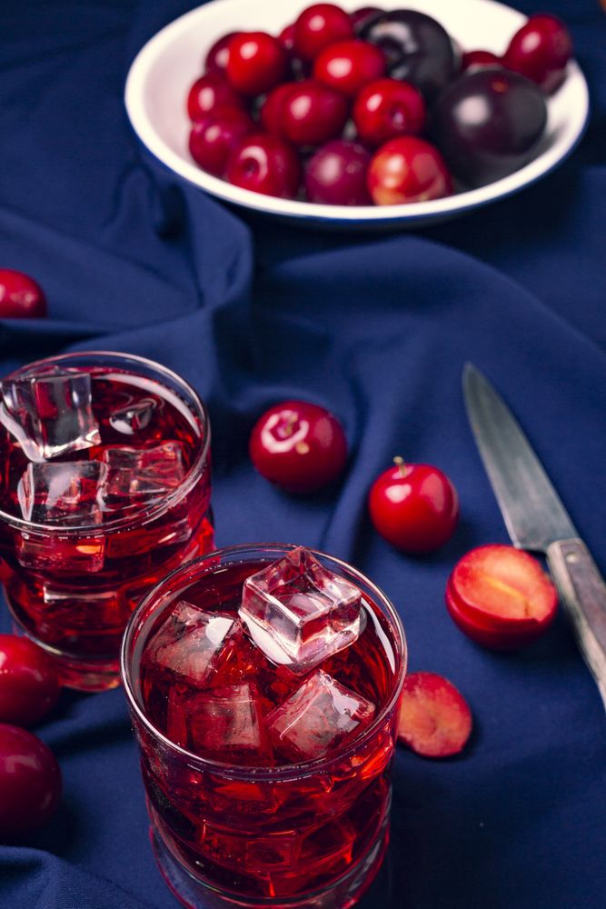 Red beverage near fresh fruits on cloth