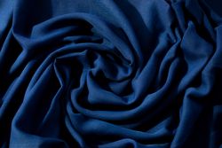 Navy or dark blue fabric wavy spiral crumpled background texture.