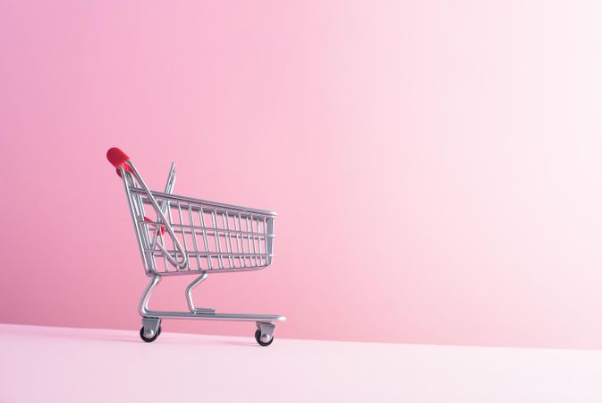 Tiny shopping cart on pink background