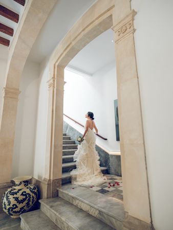 Bride in wedding dress walking upstairs on staircase in hotel
