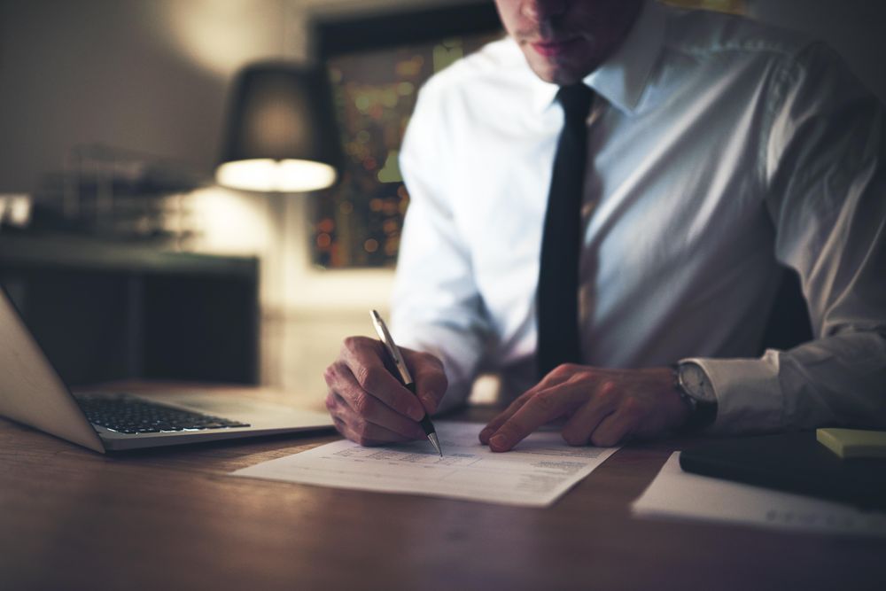 Man in shirt and tie working at desk late at night