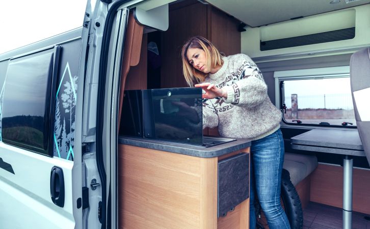 Woman in warm sweater cleaning while standing in back of van