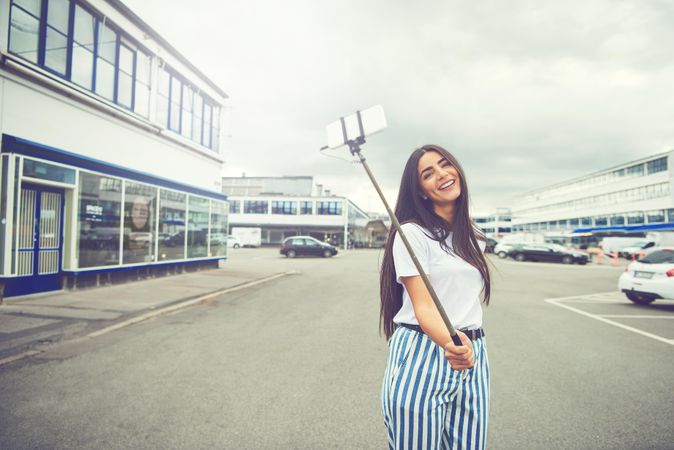 Woman posing outside with selfie stick on overcast day